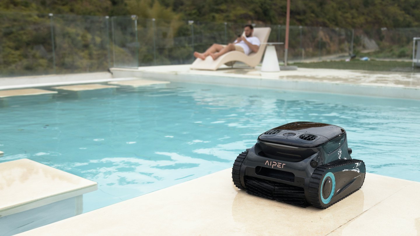 Un limpiafondos automático descansa en el borde de una piscina.