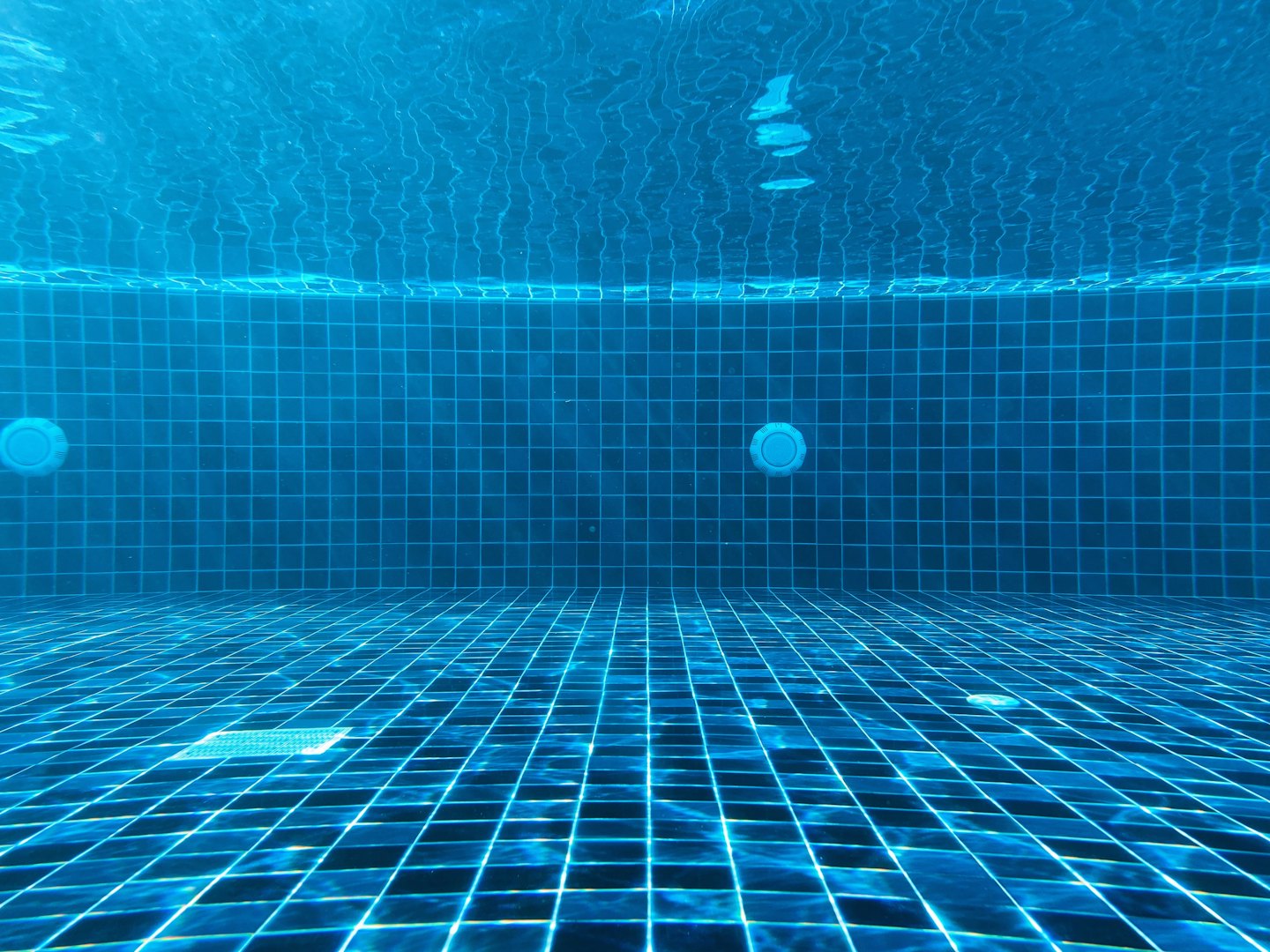 Vista submarina de una piscina limpia con mosaicos azules.