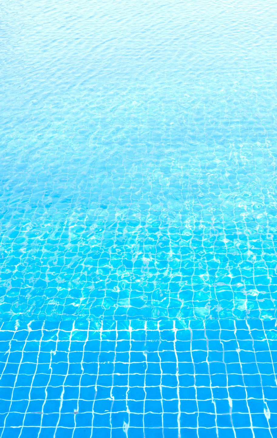 Agua azul ondulante llena una piscina de baldosas.