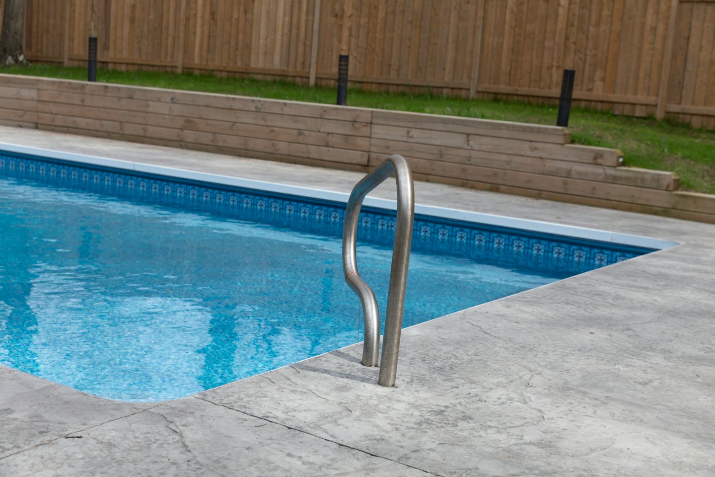Una piscina trasera con una escalera de acero inoxidable.