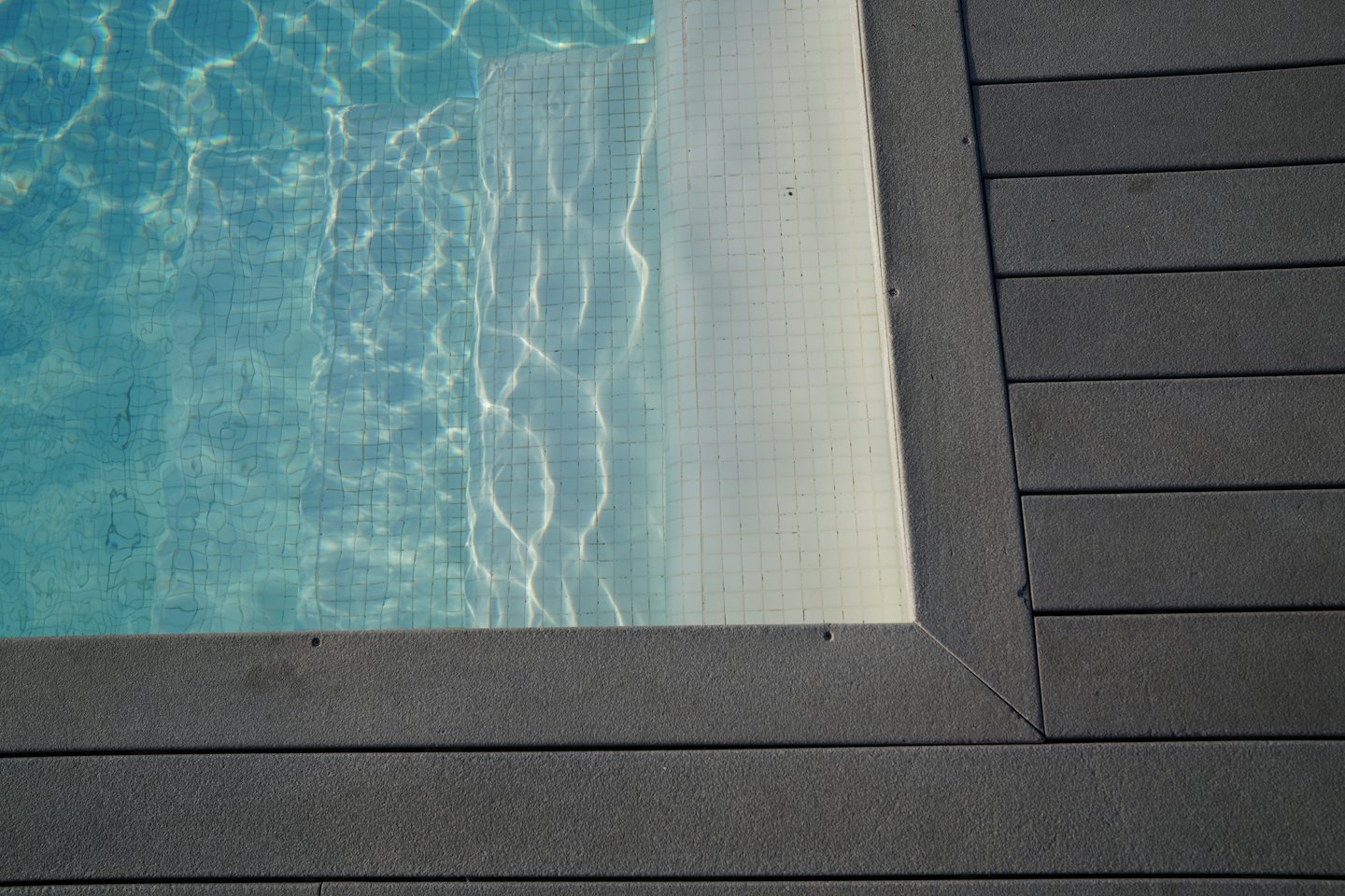 Agua clara en una piscina bordeada por una cubierta gris.