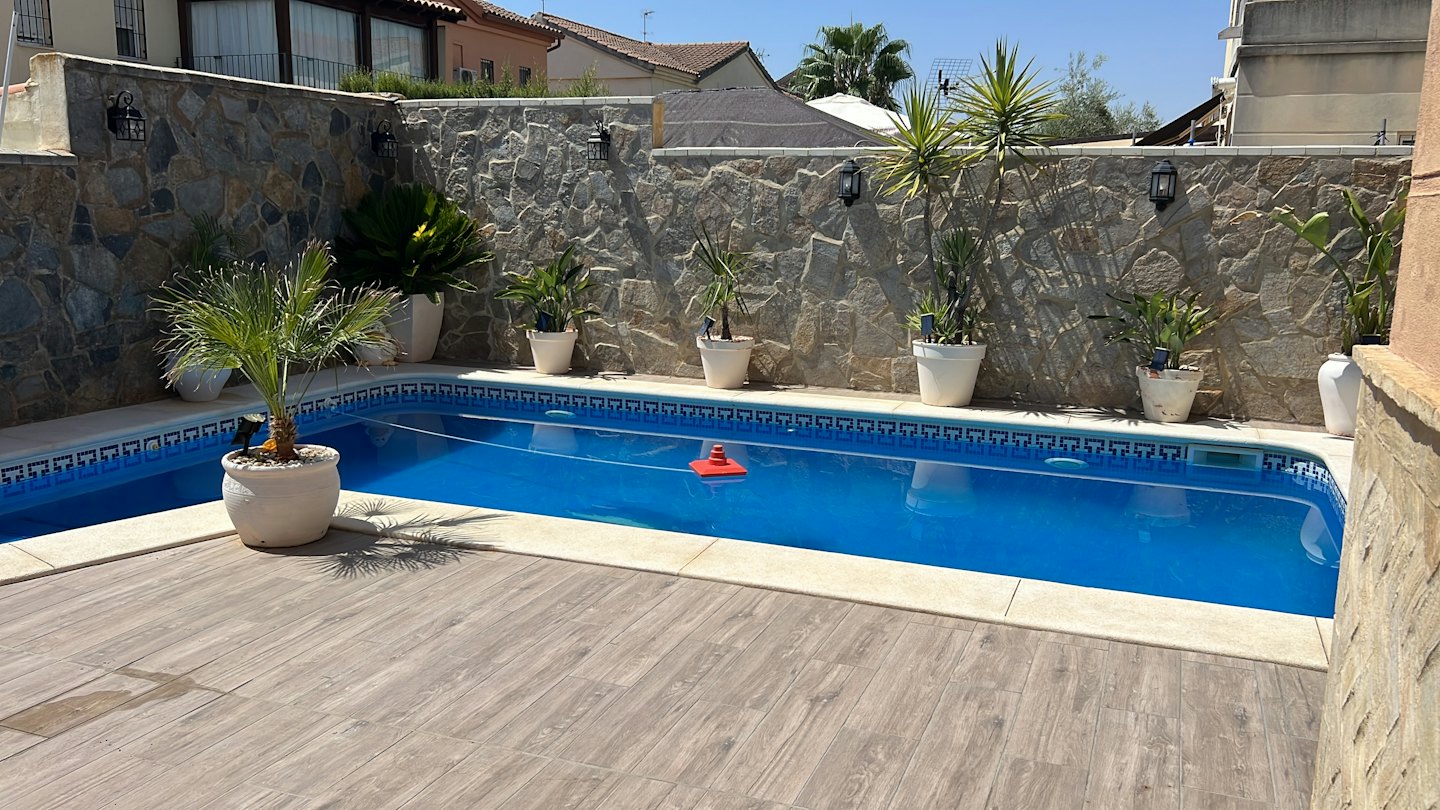 Un limpiafondos rojo flota en una piscina de patio trasero.