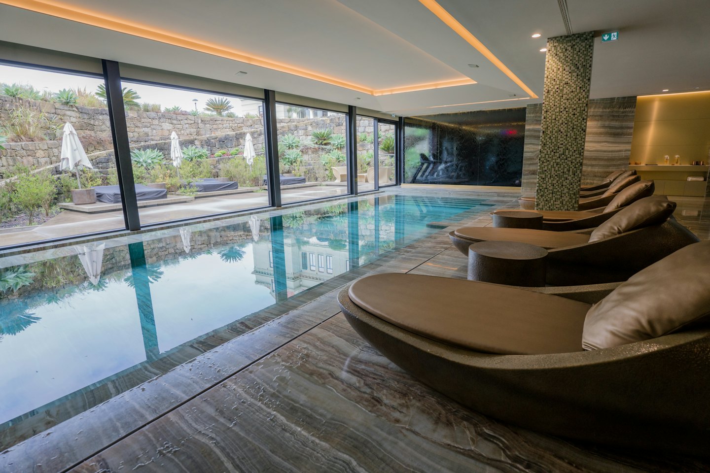 Sillas de salón marrones junto a una piscina cubierta.