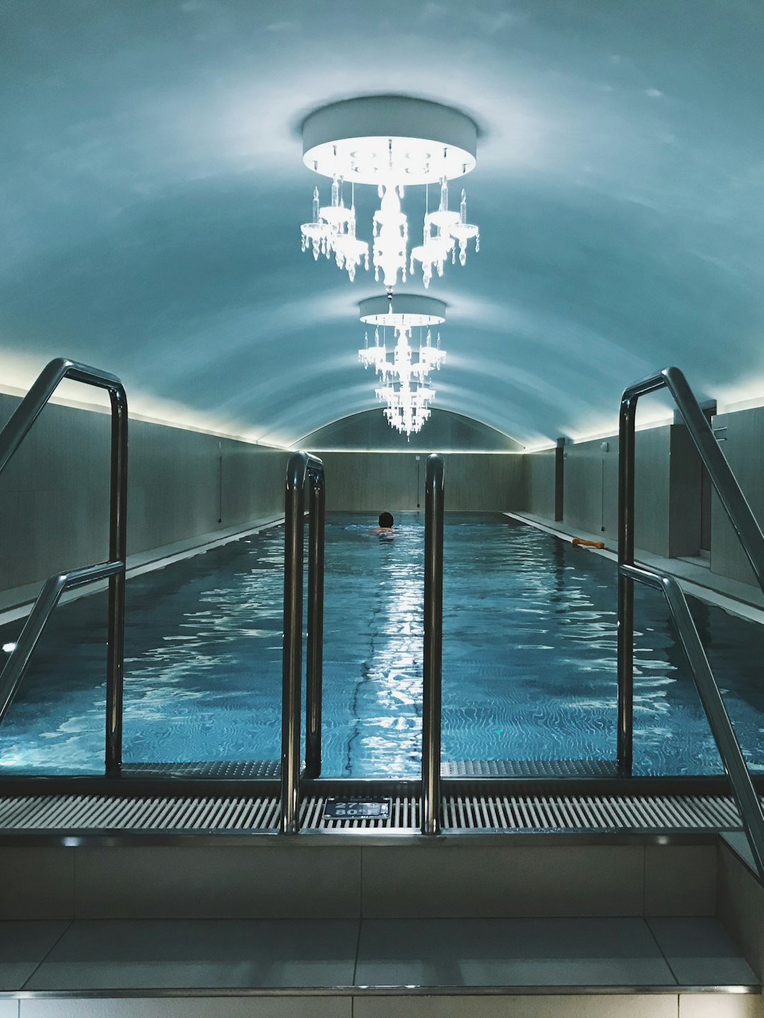 Piscina cubierta con techo abovedado y candelabros de cristal.